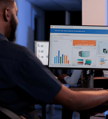 A data analyst works with multiple monitors displaying data visualizations and charts, showcasing the focus on data analysis for AI&GB's Expert Technical and Academic Consulting Services.
